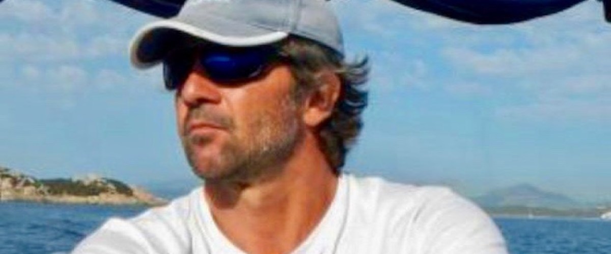 a man holding a fish in front of a body of water