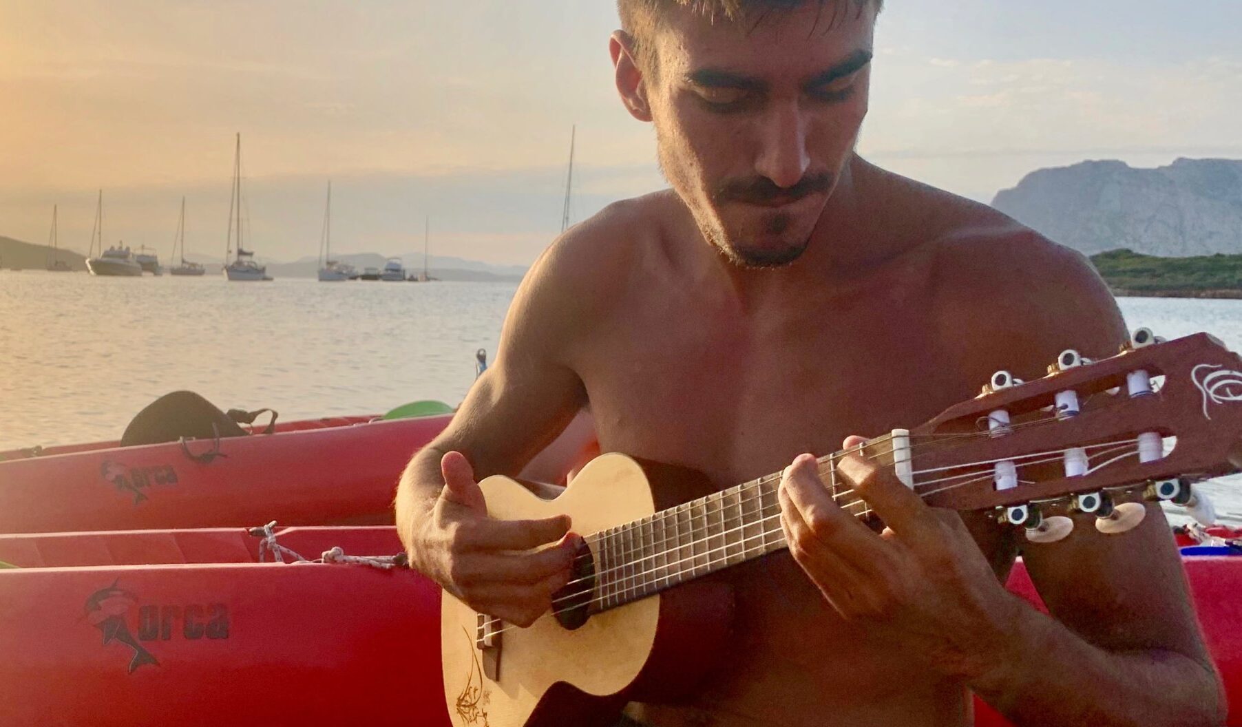 IMG_7118 2 a person holding a guitar in front of a body of water