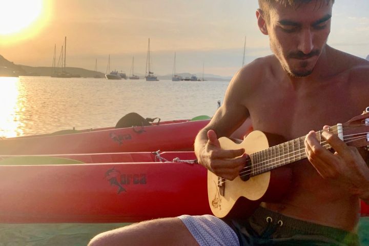 a person holding a guitar in front of a body of water