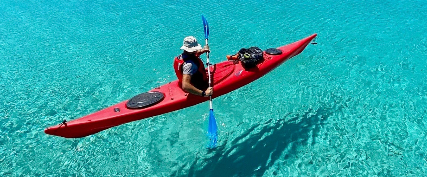 sea kayak a man riding on the back of a boat in the water